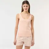 Conjunto de pijama de dos piezas en color salmón, compuesto por una musculosa de tirantes anchos con tejido acanalado y detalle de puntilla en el cuello, y un short con estampa a cuadros vichy y terminación ondulada en el ruedo.