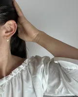 Par de aros tipo huggies dorados con dije colgante de corazón calado.