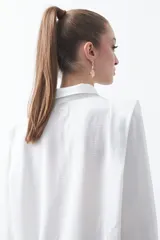 Camisa negra de estilo sastrero con cuello clásico, frente abotonado y mangas largas con puños ajustados. Presenta un diseño con hombreras sutiles que aportan estructura a la prenda.
