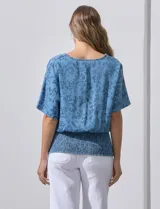 Blusa celeste con estampado floral, escote en V y ruedo smock.