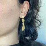 Aros colgantes plateados con tres piezas geométricas unidas por argollas.