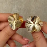 Par de aros tipo caravanas con diseño de flor de cuatro pétalos con textura estriada en acabado plateado.