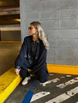 Conjunto negro de pana compuesto por una chaqueta con cuello de cuero sintético, cierre frontal con cremallera y bolsillos con solapa, y un pantalón de corte recto con bolsillos laterales.