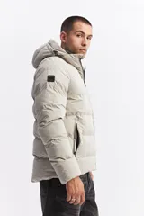 Campera puffer con capucha, diseño acolchado, cierre frontal y bolsillos laterales. Presenta un interior en contraste de color verde oliva.