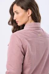 Campera de pana color rosado con interior de corderito sintético. Cuenta con cierre frontal de botones metálicos, cuello camisero, bolsillos con solapa en el pecho y mangas largas.