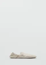 Zapatos tipo ballerinas planas de piel ovina en color blanco, con punta redonda, diseño sin cordones y detalle de fruncido elástico en el talón.