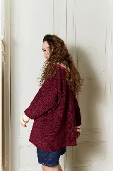 Buzo de punto bordó estilo oversize, con cuello babero amplio con volados y franjas en tonos amarillo y rojo, manga larga con terminación en volados.