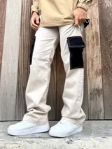 Pantalón de gabardina color beige con bolsillos cargo negros y corte wide leg.