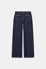 Jeans de mezclilla azul oscuro, tiro medio, corte pierna ancha (wide leg). Presenta bolsillos delanteros de parche con detalle de cadena metálica decorativa.