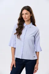 Camisa de lino celeste con cuello clásico, cierre frontal con botones y mangas tres cuartos terminadas en volados.