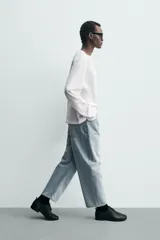 Jeans de hombre color azul claro con efecto lavado, de corte relajado desde la cadera que se estrecha ligeramente en el bajo. Tienen tiro medio, cinco bolsillos y cierre frontal con cremallera y botón.