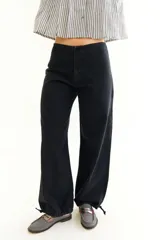 Pantalón de jean negro de tiro bajo con corte recto y ajuste mediante cordones en la botamanga, permitiendo un estilo tipo balloon.