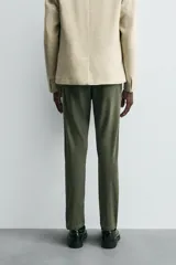Pantalón chino de corte ajustado, color beige, con bolsillos laterales y bolsillos traseros de vivo. Cuenta con cierre frontal de cremallera y botón.