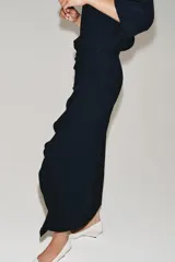 Vestido midi de cuello redondo y manga corta, confeccionado en tejido fluido color azul marino. Presenta un diseño con detalle de drapeado y volado lateral en la parte delantera, con cierre en la espalda mediante abertura y botón.