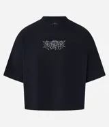 Remera negra de algodón con corte oversized, cuello redondo, mangas cortas y estampa tribal blanca en el pecho.