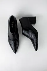 Botines de caña baja con acabado acharolado y textura efecto cocodrilo. Presentan punta fina, cierre lateral y taco cuadrado de altura media.