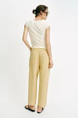 Pantalón de tiro medio color amarillo, con cintura elástica, bolsillos de plastrón en el delantero y pernera holgada que se estrecha hacia el tobillo. Cuenta con cierre frontal de cremallera y botón.