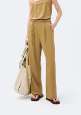 Pantalón de corte recto color beige con pinzas en la parte delantera y tira ajustable a modo de cinturón con nudos decorativos.