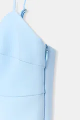 Top negro de escote en pico con tirantes finos ajustables, diseño entallado y cierre lateral con cremallera.