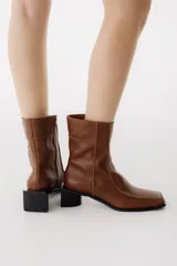 Botas cortas de cuero color marrón con punta cuadrada, cierre lateral con cremallera y tacón bloque negro.