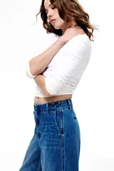 Pantalón de denim de algodón rígido, de corte recto y tiro alto, con pliegues frontales y traseros, bolsillos laterales al bies y cierre oculto.