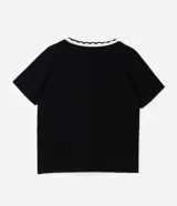 Blusa de viscolycra color beige con escote en V y cuello doble en tono negro con borde de ondas, de mangas cortas y corte amplio.