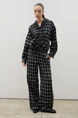 Pantalón de corte amplio y tiro medio-alto, confeccionado en tejido liviano con estampado a cuadros. Presenta cintura elastizada con lazo regulable y bolsillos laterales.