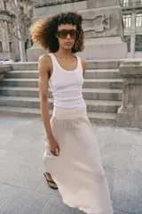 Falda midi de tiro alto con detalle de frunces en la cintura y tejido satinado con efecto arrugado. Presenta un corte fluido y cierre lateral con cremallera oculta.