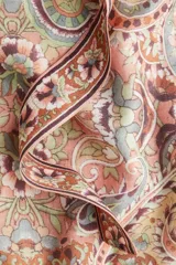 Vestido largo sin mangas, con cuello alto y abertura en la nuca. Presenta un estampado paisley en tonos tierra, rosados y celestes, con frunces a la altura de la cadera que generan una falda acampanada con vuelo.