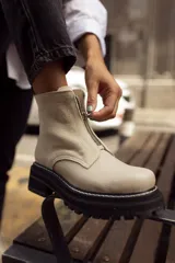 Bota corta de cuero con textura granulada y gamuza, color beige, con cierre frontal y suela track negra con costuras visibles.