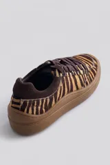 Championes urbanos de cuero con estampa animal print tipo tigre en tonos marrones y beige. Tienen suela de goma marrón y cordones al tono.