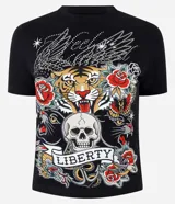 Remera de algodón con escote redondo y mangas cortas, de corte ajustado al cuerpo y color negro. Presenta un estampado frontal de estilo tattoo flash con un tigre, una calavera, panteras y rosas, acompañado de la inscripción "Liberty" y detalles de brillos termosellados.