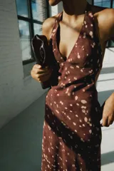 Vestido midi satinado color marrón con estampado de lunares difuminados, de cuello halter con tiras ajustables para atar en la espalda y escote en V.