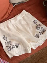 Short elastizado color marfil con delicados bordados de flores en tono azul marino en la parte frontal.