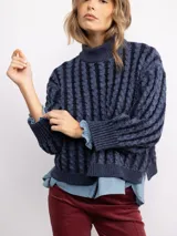 Sweater de punto con diseño de trenzas verticales, cuello alto y corte holgado. Presenta mangas largas con puños acanalados y un largo que llega a la cadera.