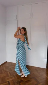 Vestido largo sin mangas, con escote palabra de honor y pañuelo incorporado al cuello. Presenta un estampado geométrico en tonos celeste, verde y blanco, con aberturas laterales en la falda.
