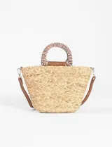 Bolso tipo canasto de rafia color beige, con asas rígidas de madera y correa de cuero sintético marrón.