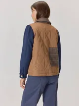 Campera de diseño híbrido con frente acolchado en color tostado, solapas y cuello en tejido de lana con patrón de cuadros tipo príncipe de gales, y mangas en paño de lana color azul marino. Cuenta con cierre frontal de botones.