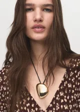 Vestido largo de corte evasé con estampado floral pequeño sobre fondo marrón. Presenta cuello en pico, mangas largas acampanadas y tejido plisado con caída fluida.