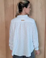 Blusa de manga larga con estampado de rayas verticales finas en tono beige. Presenta cuello redondo con volados, cierre frontal parcial con botones y puños con volados.