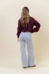 Pantalón de jean estilo wide leg, color celeste claro, con tiro medio, cinco bolsillos y cierre frontal con botón y cremallera.