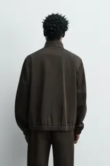 Cazadora de corte regular confeccionada en tejido de lana y algodón de origen italiano. Presenta cuello alto ajustable con botones, cierre frontal con cremallera de doble dirección, bolsillos laterales con solapa y puños y ruedo con acabado elástico.