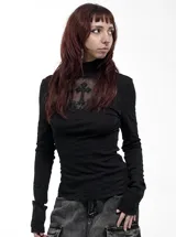 Remera de manga larga negra con cuello alto, confeccionada en viscosa y elastano. Presenta un panel frontal de encaje transparente en el pecho con un aplique de cruz bordada y detalles de cruces en las mangas.
