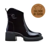 Bota de cuero charol color negro, con caña corta, hebilla lateral y taco cuadrado.