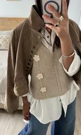 Chaleco de punto color beige con escote en V, diseño de trenzas verticales y tres flores tejidas en relieve.