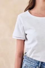 Remera de algodón de corte clásico y entallado, con cuello redondo y mangas cortas con detalle de costura decorativa en el borde.