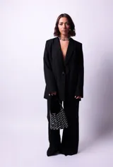 Cartera tipo hobo de PU acharolada color negro, cubierta de tachas plateadas.