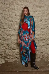 Vestido largo de seda estampado con motivos paisley en tonos turquesa, rojo y naranja. Tiene cuello bote, corte recto y aberturas laterales. Incluye un pañuelo al cuello con el mismo estampado.