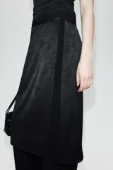Falda midi de tiro medio en tejido jacquard con diseño floral tono sobre tono. Presenta un corte recto con una abertura lateral y cierre oculto con botón y cremallera.