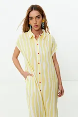 Vestido camisero amarillo con rayas verticales blancas, sin mangas y con botones rojos.